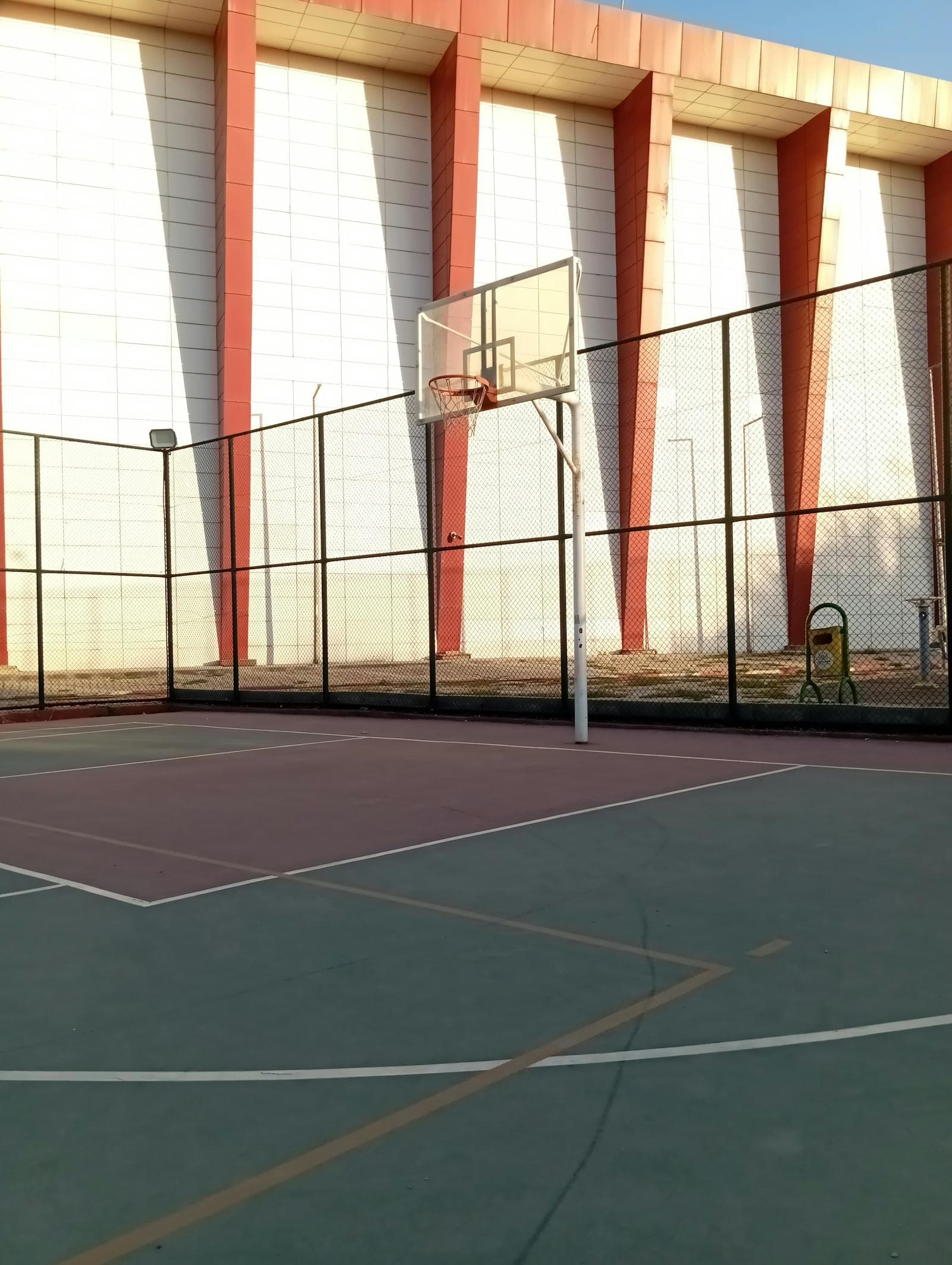 An empty outdoor basketball court in warm evening light